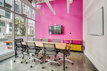 a conference room with a pink wall and a table with chairs at L Seven, San Francisco, 94103