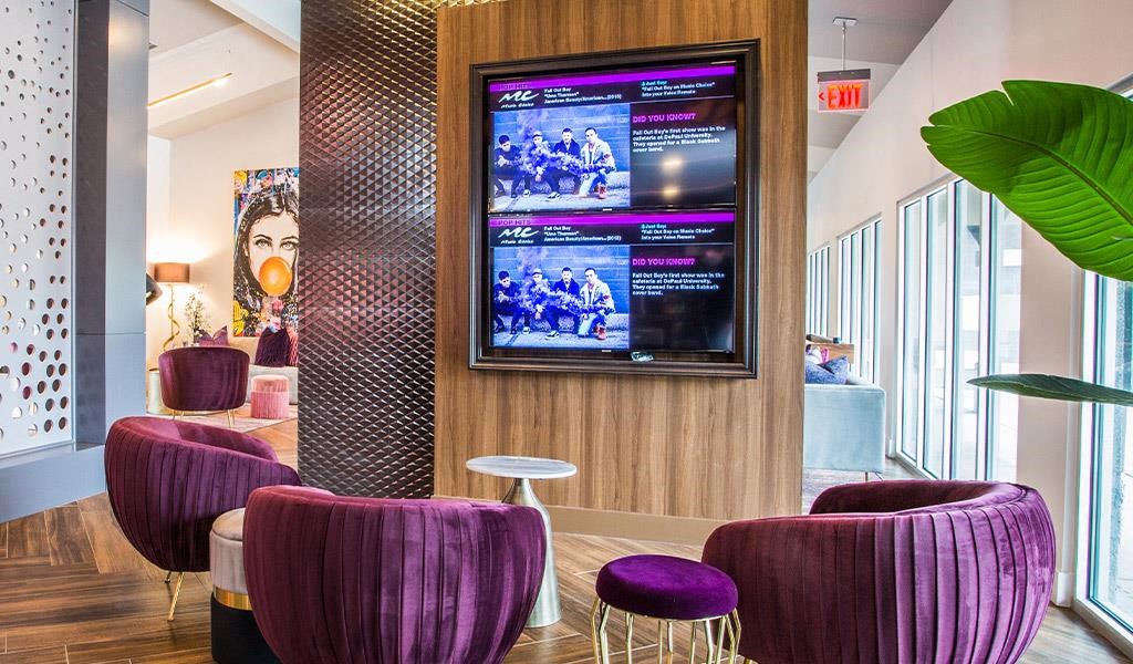 a lobby with purple chairs and a tv on the wall
