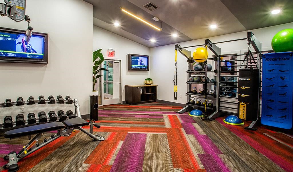 a gym with weights and a tv on the wall