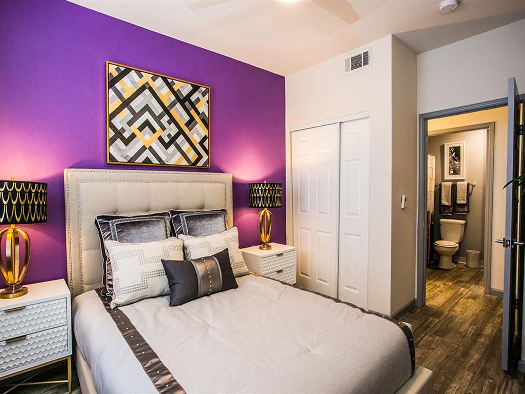 a bedroom with a large bed and a purple accent wall