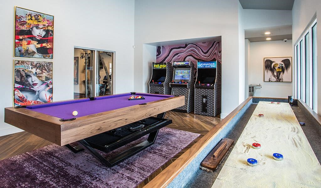 a game room with a purple pool table and arcade games