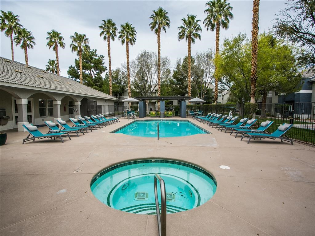 a resort style pool with blue lounge chairs and palm trees