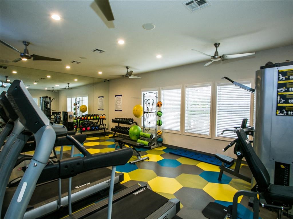 a gym with weights and other equipment in a room with windows