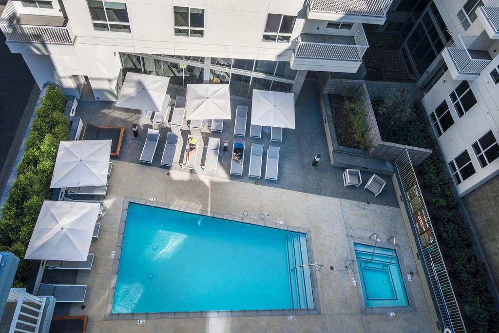 a pool is surrounded by chairs and umbrellas in an apartment building