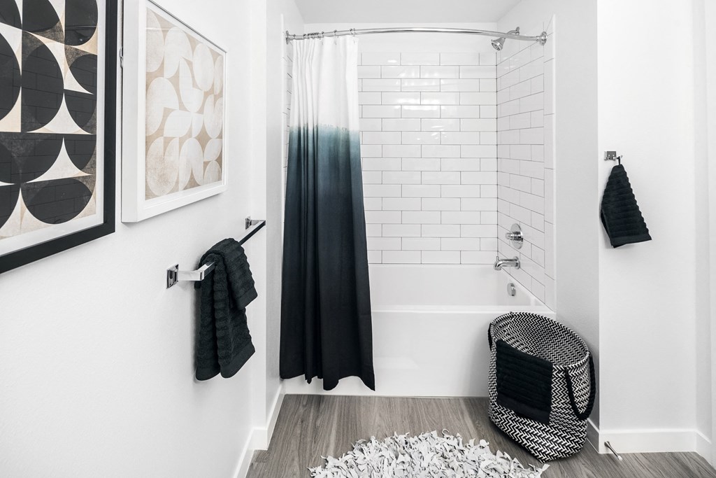 a white bathroom with a black shower curtain and a white tub