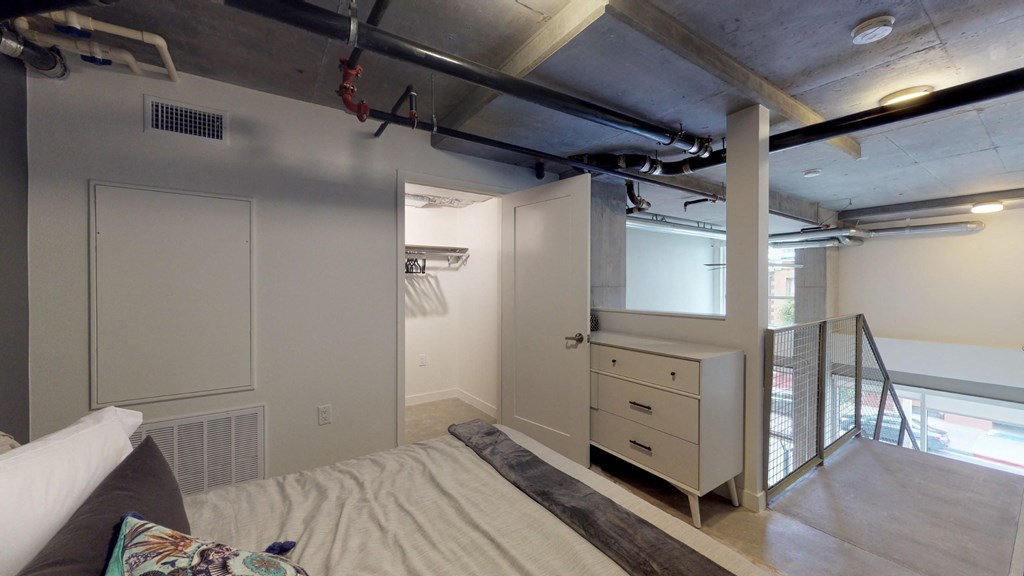 a bedroom with a bed and a closet and a stairwell