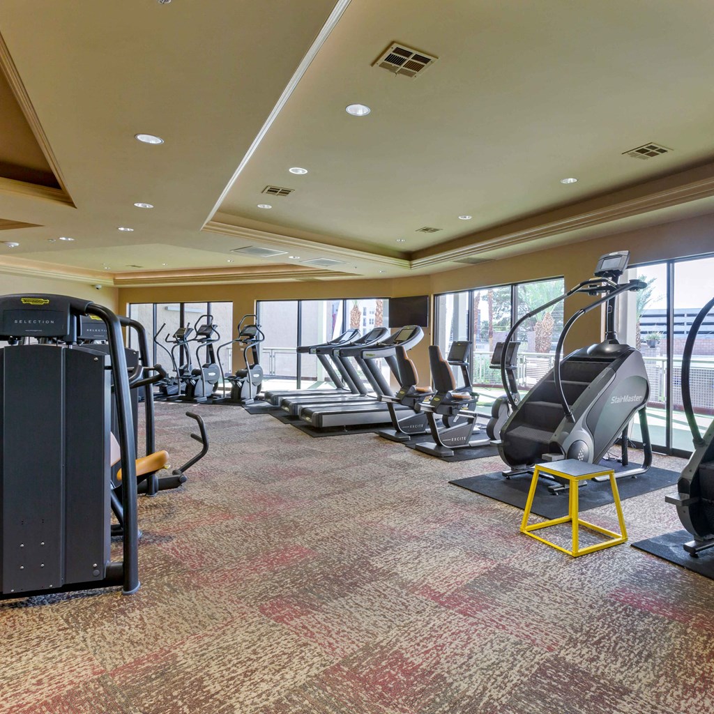 a gym with cardio equipment in a room with windows at The Rays at Vegas Towers Apartments, Las Vegas, NV 89119