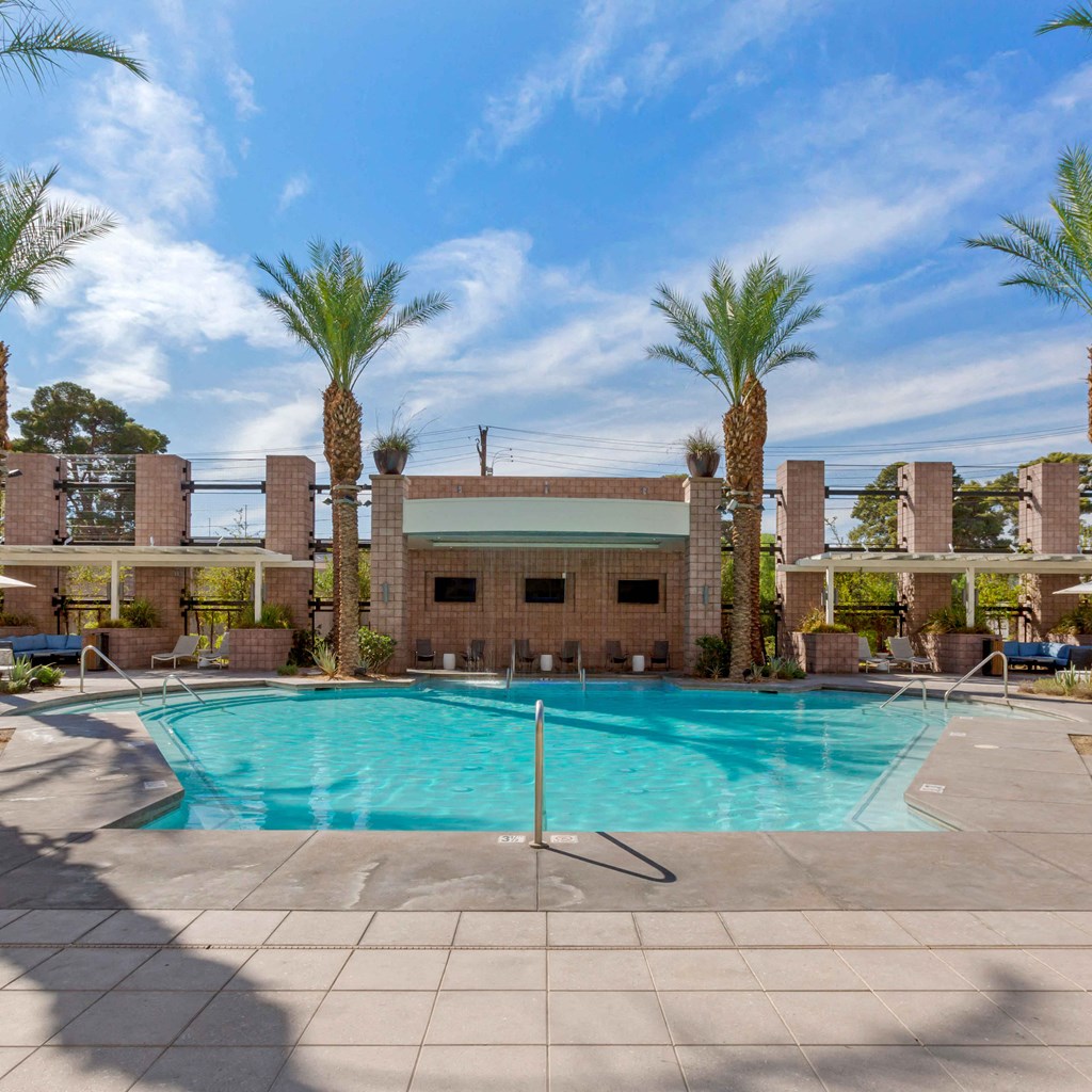 a swimming pool with palm trees and a building in the background at The Rays at Vegas Towers Apartments, Las Vegas