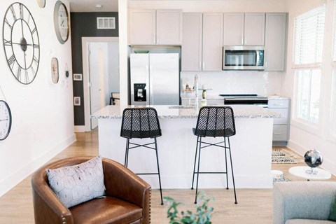 a white kitchen with bar stools and a counter at The Merchant Apartments, Charleston, SC