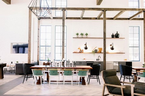 Resident lounge with high ceilings and wooden pergola with various cafe seating and farm tables at The Merchant Apartments, South Carolina