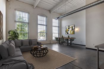 a living room with a gray couch and a table at Highland Mill Lofts, Charlotte, NC 28205