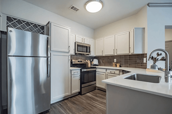Upgraded Kitchen with Stainless-Steel Appliances, Backsplash, and Custom Cabinetry and Plank Flooring at Creekside at Legacy in Plano, Texas 75024