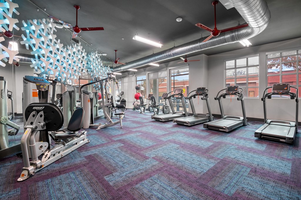 a gym with treadmills and other exercise equipment in a building with windows at South Side Flats, Dallas, 75215