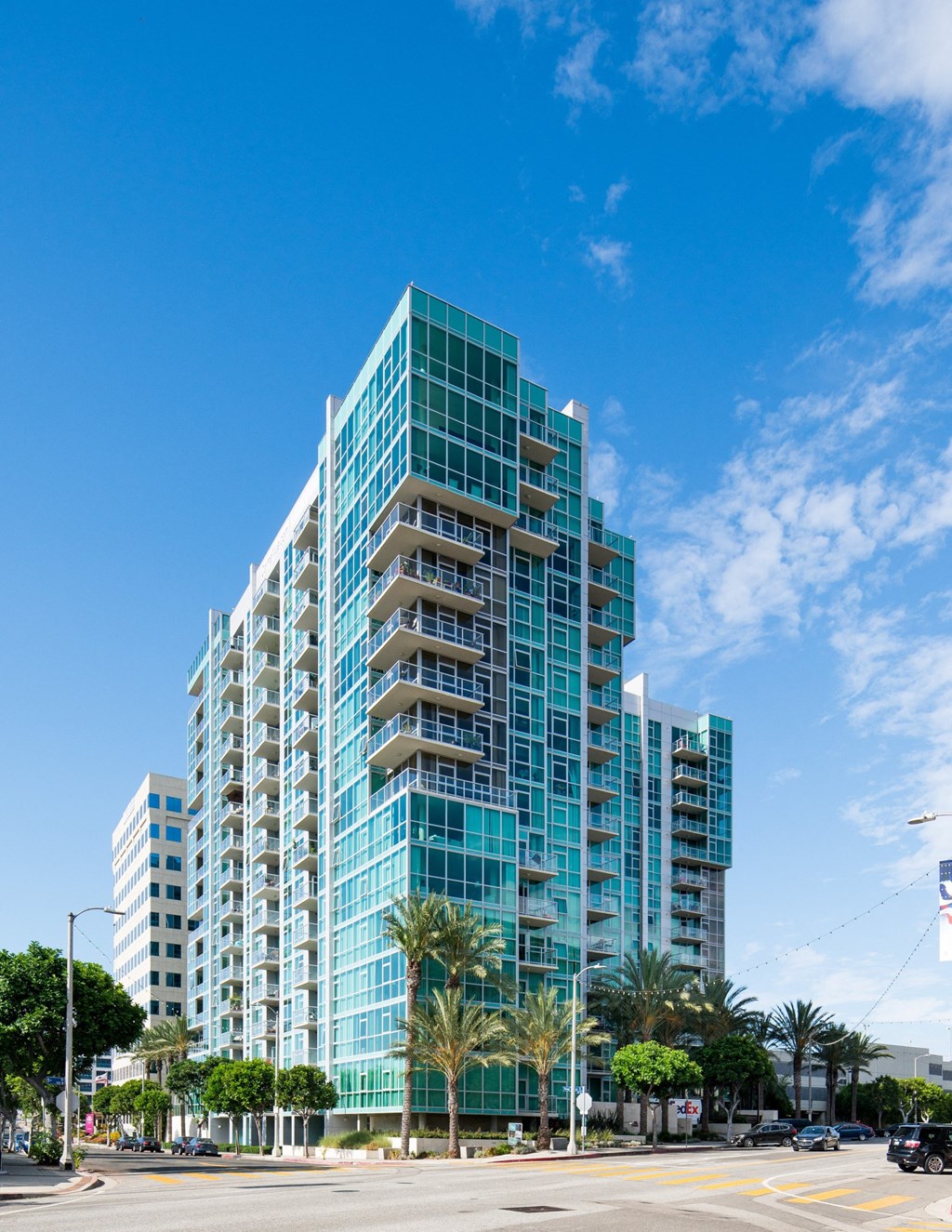 A tall building with blue glass windows stands on a street corner at Vue, San Pedro, CA