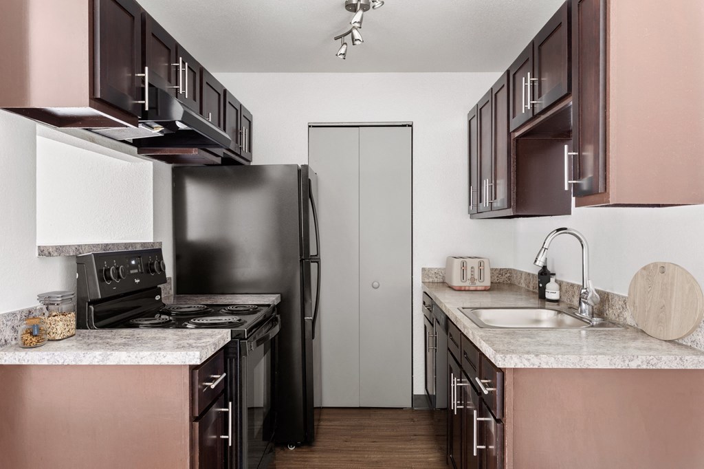 a kitchen with black appliances and white counter tops and brown cabinets  at Verona, Littleton, CO, 80123