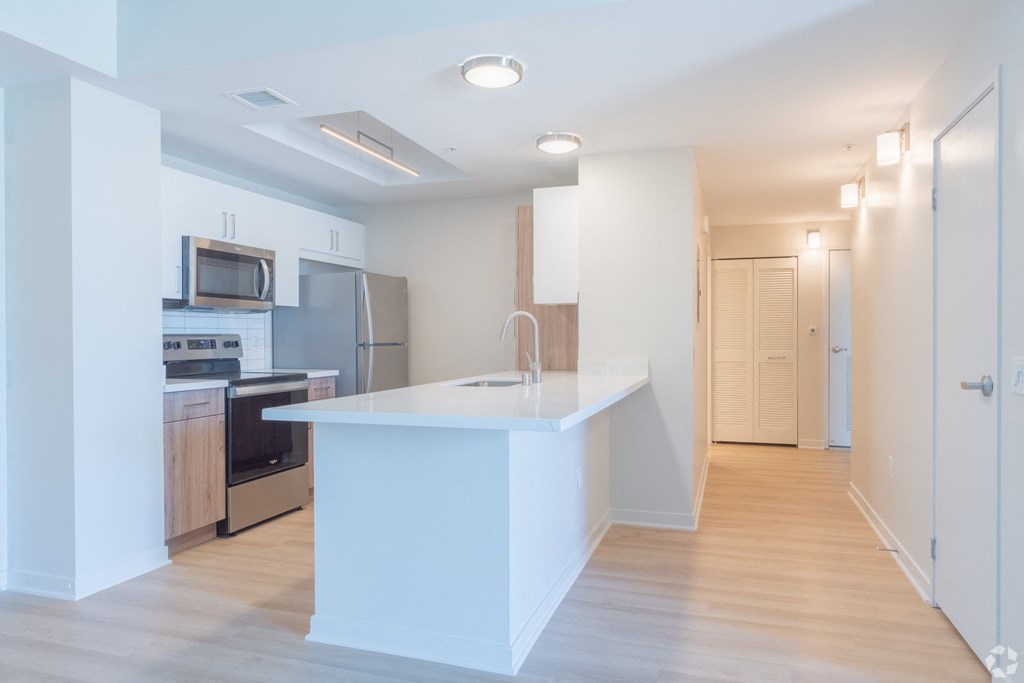 a white kitchen with a large island and stainless steel appliances at Vue, San Pedro, CA 90731