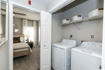 a white washer and dryer in a room with a bedroom