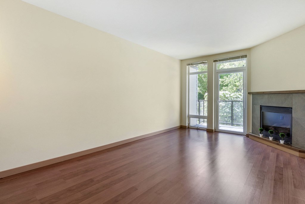 an empty living room with hardwood floors and sliding glass doors leading to a patio at 128 on State, Kirkland, WA