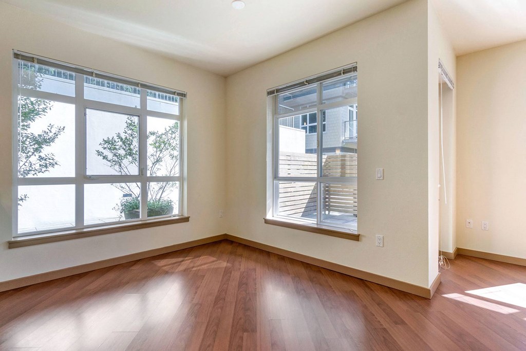 a spacious living room with plank flooring and two large windows  at 128 on State, Kirkland, WA