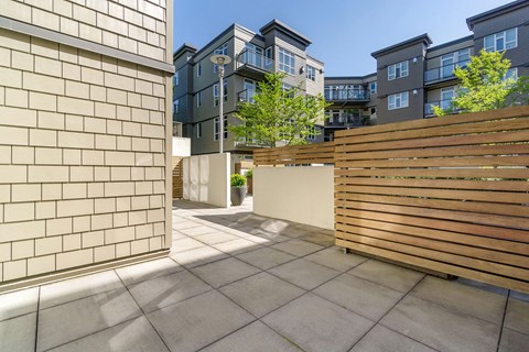 a private patio with a wood slatted privacy fence in front of an apartment building at 128 on State, Kirkland, Washington