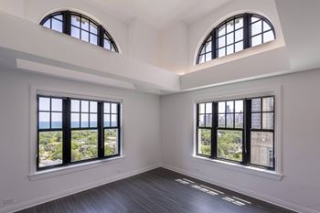 an empty living room with two windows and a wood floor  at The Belden Stratford, Chicago