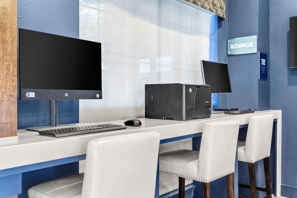 a computer desk with three chairs and a monitor on it at Aston at Cinco Ranch, Texas