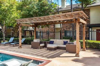 a covered patio with couches and chairs next to a pool at Aston at Cinco Ranch in Katy, 77450