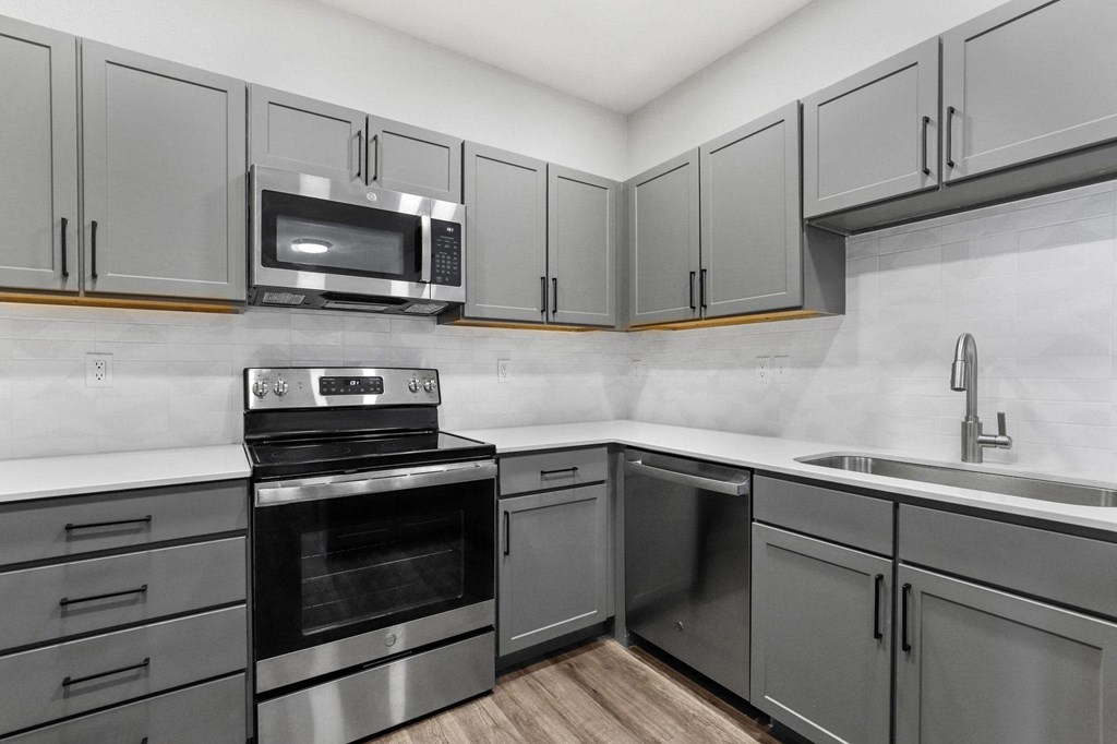 an empty kitchen with stainless steel appliances and white cabinets at Switchback on Platte Apartments, Littleton