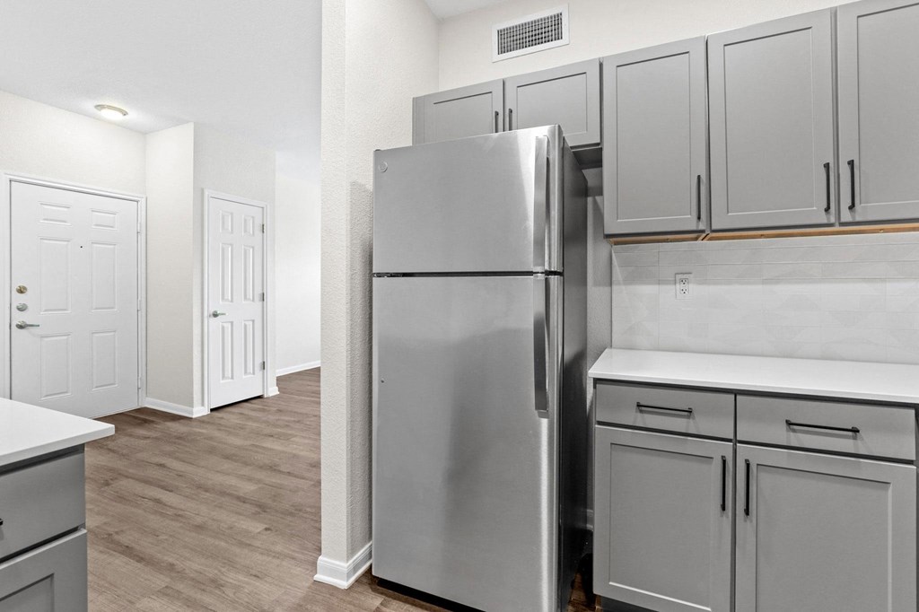 a renovated kitchen with stainless steel refrigerator and white cabinets a renovated kitchen with stainless steel refrigerator and white cabinets at Switchback on Platte Apartments, Littleton, Colorado
