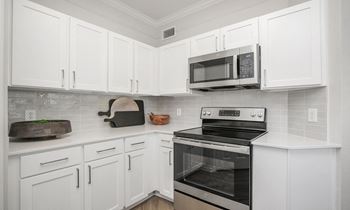 a kitchen with white cabinets and a stove and a microwave at Sladestone Shadow Creek, Pearland