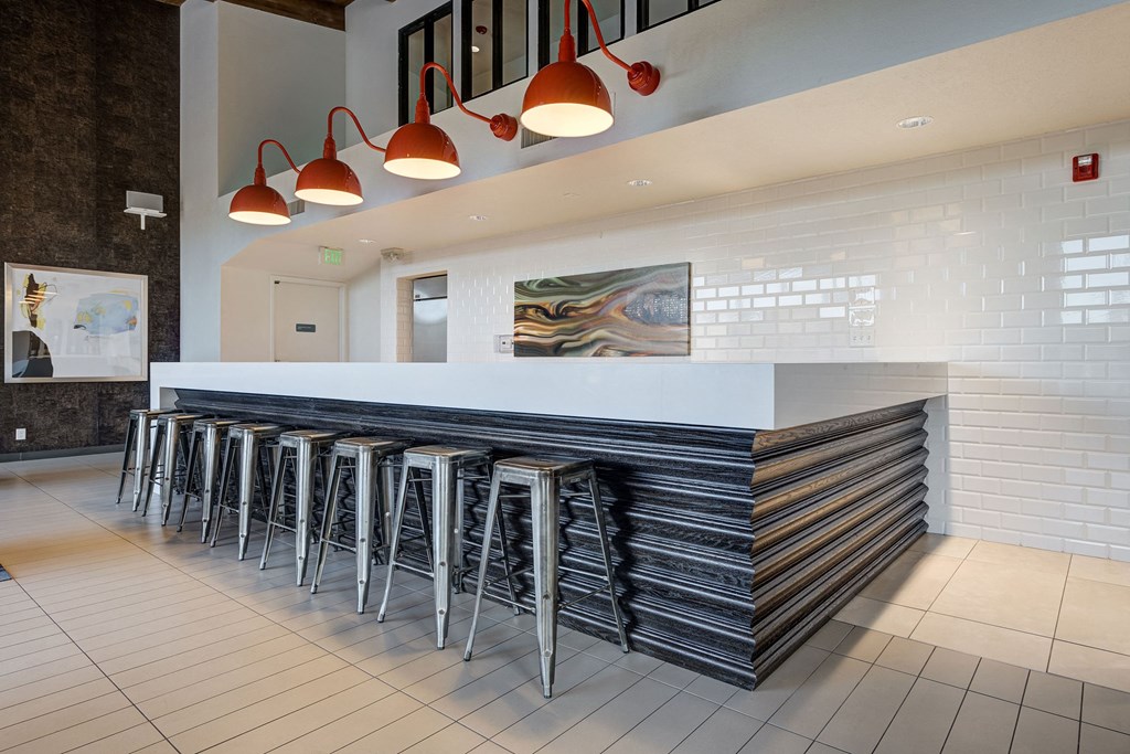 a long bar with stools in front of a white counter in a hotel lobby at Ashford Belmar Apartments, Lakewood, Colorado