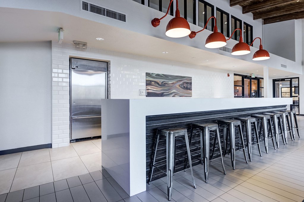 a row of bar stools in front of a long bar with white tiles at Ashford Belmar Apartments, Lakewood, 80226
