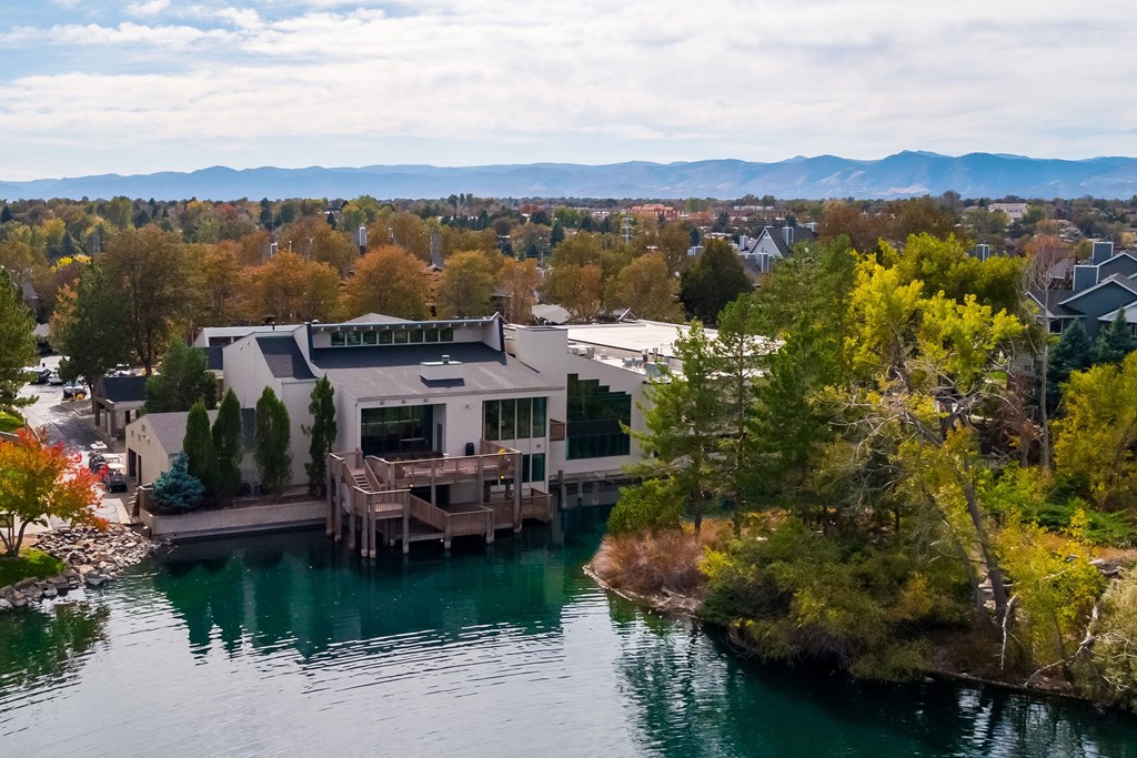 an aerial view of a house on a lake with mountains in the background at Ashford Belmar Apartments, Lakewood, CO 80226