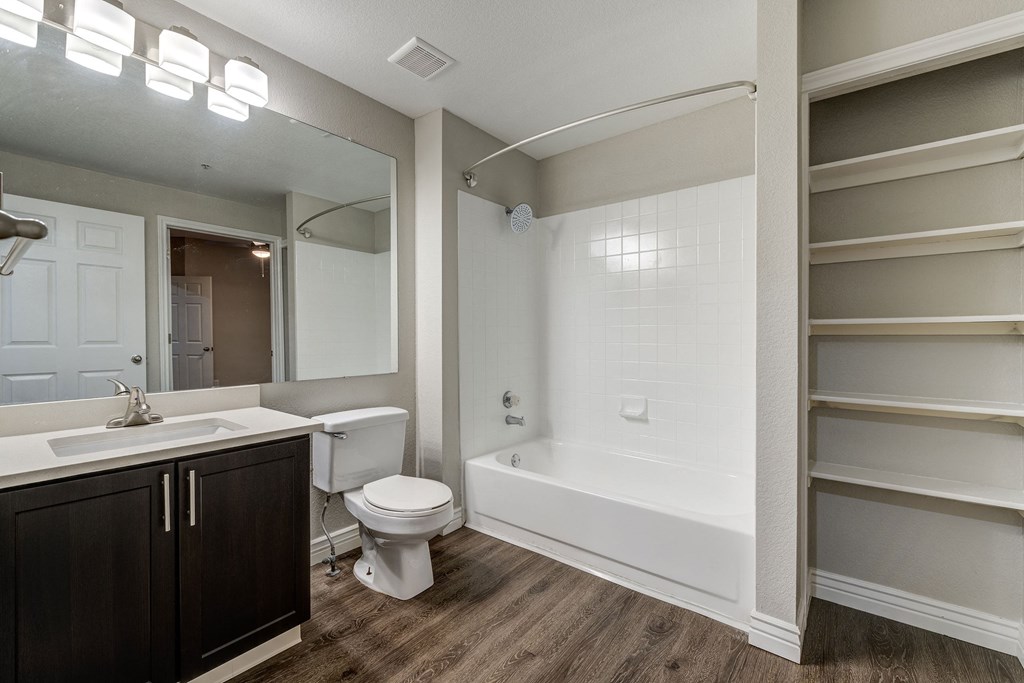 a bathroom with a toilet sink and tub and a mirror at Ashford Belmar Apartments, Lakewood, Colorado