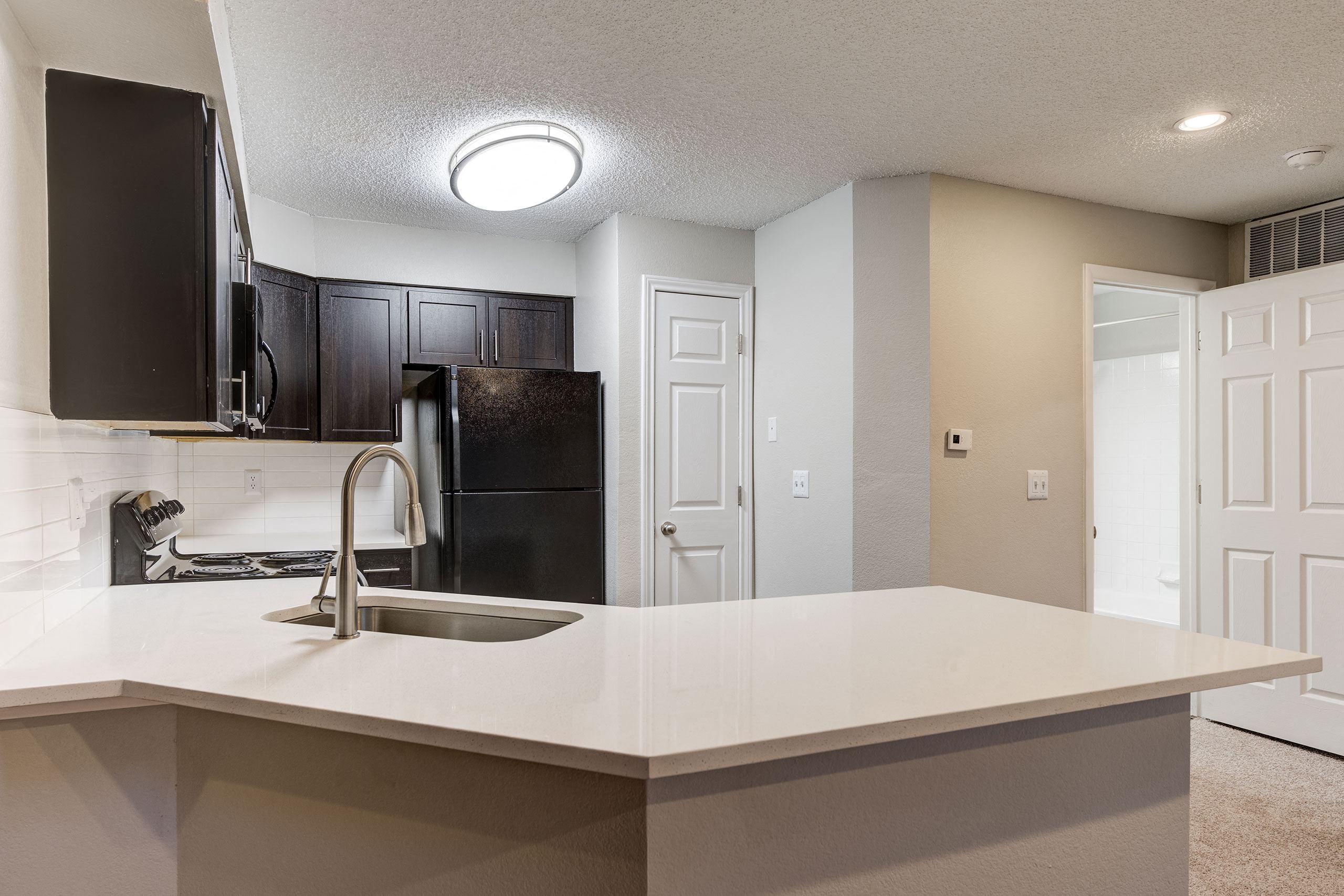 an empty kitchen with a sink and a refrigerator at Apartments at Denver Place, Colorado, 80202
