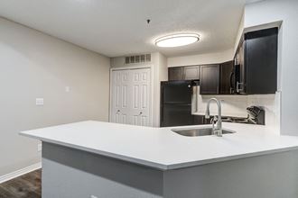 an empty kitchen with a sink and a refrigerator at Apartments at Denver Place, Colorado