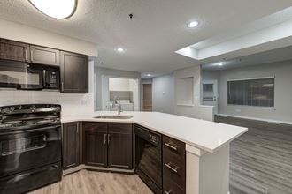 a kitchen with a white counter top and black appliances at Apartments at Denver Place, Denver