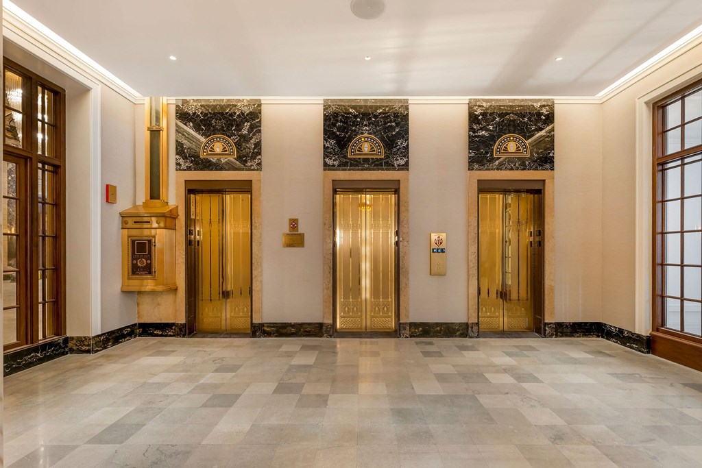 the lobby of a building with gold doors and a marble floor  at The Belden Stratford, Chicago