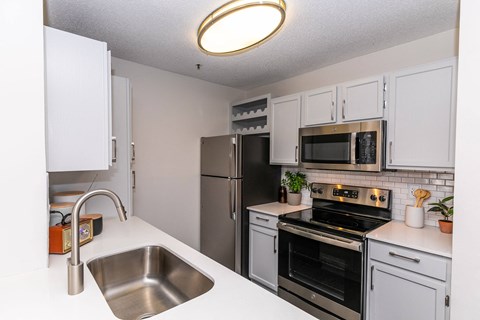 a kitchen with stainless steel appliances and white cabinets at Briarcliff Apartments, Georgia