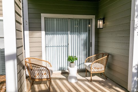 a porch with two rattan chairs and a vase with a plant at Briarcliff Apartments, Atlanta