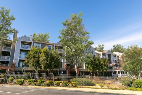 an apartment building with a fence and trees in front of it at Briarcliff Apartments, Atlanta