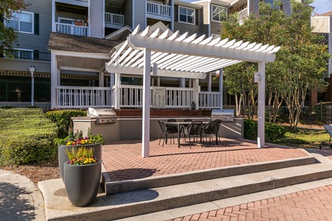 a white pergola on a brick patio with a table and chairs at Briarcliff Apartments, Georgia, 30329