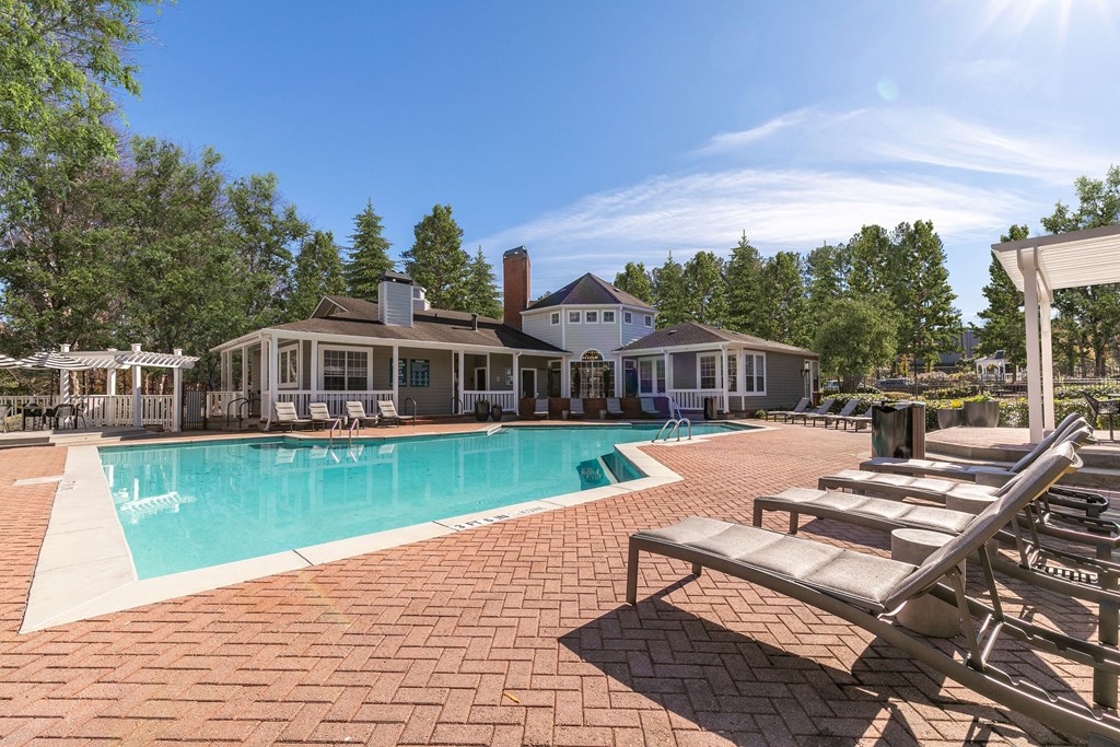 a swimming pool with lounge chairs and a house in the background a swimming pool with lounge chairs and a house in the background at Briarcliff Apartments, Georgia