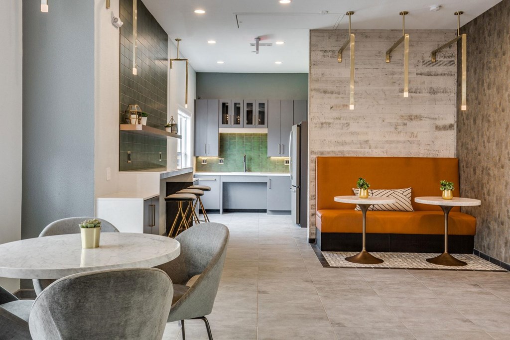 a dining area with tables and chairs and a kitchen in the background at Carrington at Barker Cypress, Cypress, TX
