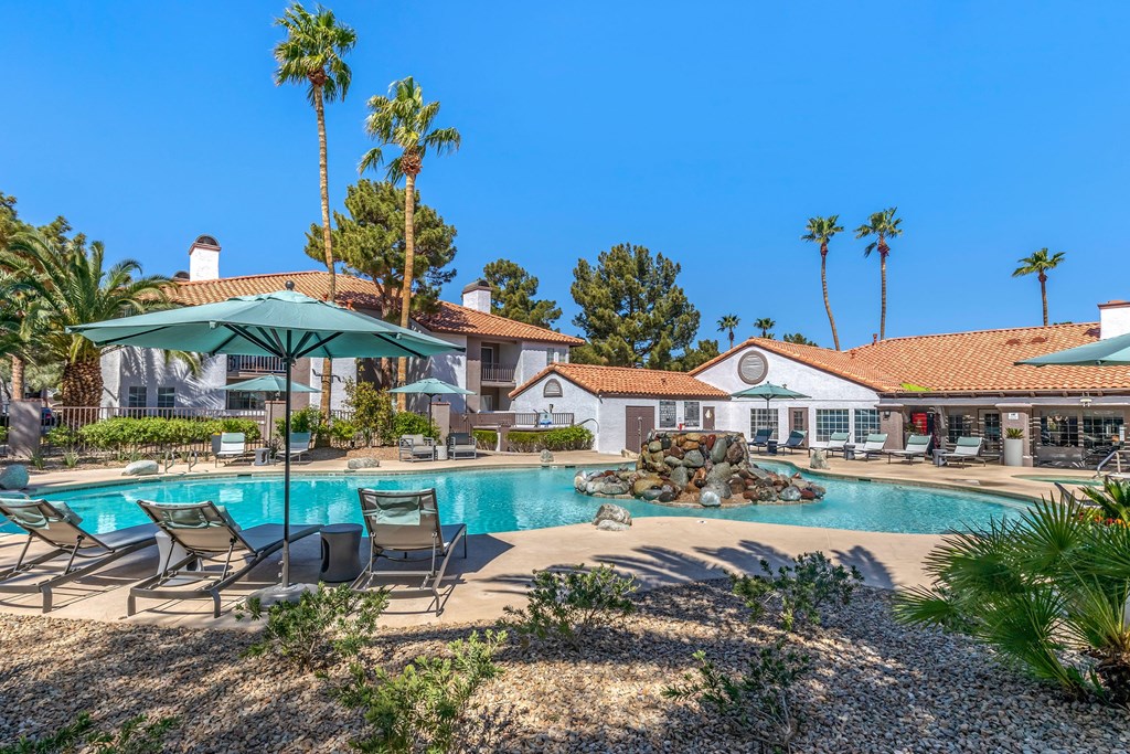 a swimming pool with chairs and umbrellas in front of a resort style pool