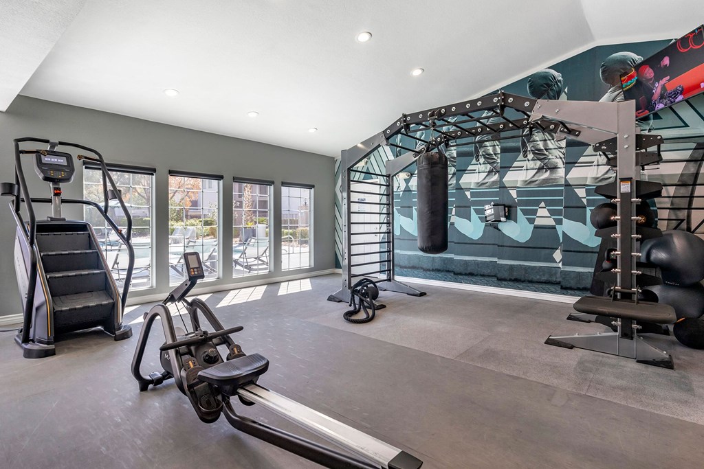 a gym with weights and equipment and a wall with a punching bag and a ladder