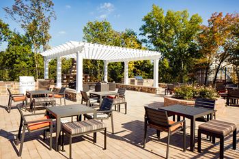 an outdoor patio with tables and chairs and a pergola  at Heights at Glen Mills, Glen Mills, 19342