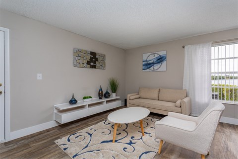 A living room with a white couch, a white coffee table, and a white chair.