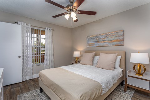 A bedroom with a bed, two lamps, and a painting on the wall.