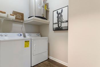 a laundry room with a washer and dryer and a painting on the wall at Madison on the Meadow, Stafford, 77477
